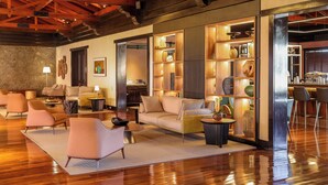 A spacious living area with a wooden ceiling, a sofa set, and a bar area with shelves of decorative items. - Sanma Hotel  (Foz do Iguaçu)