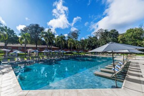 Una piscina al aire libre, sombrillas, sillones reclinables de piscina