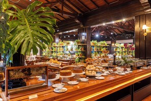 A buffet with various food items and a large plant. - Sanma Hotel  (Foz do Iguaçu)