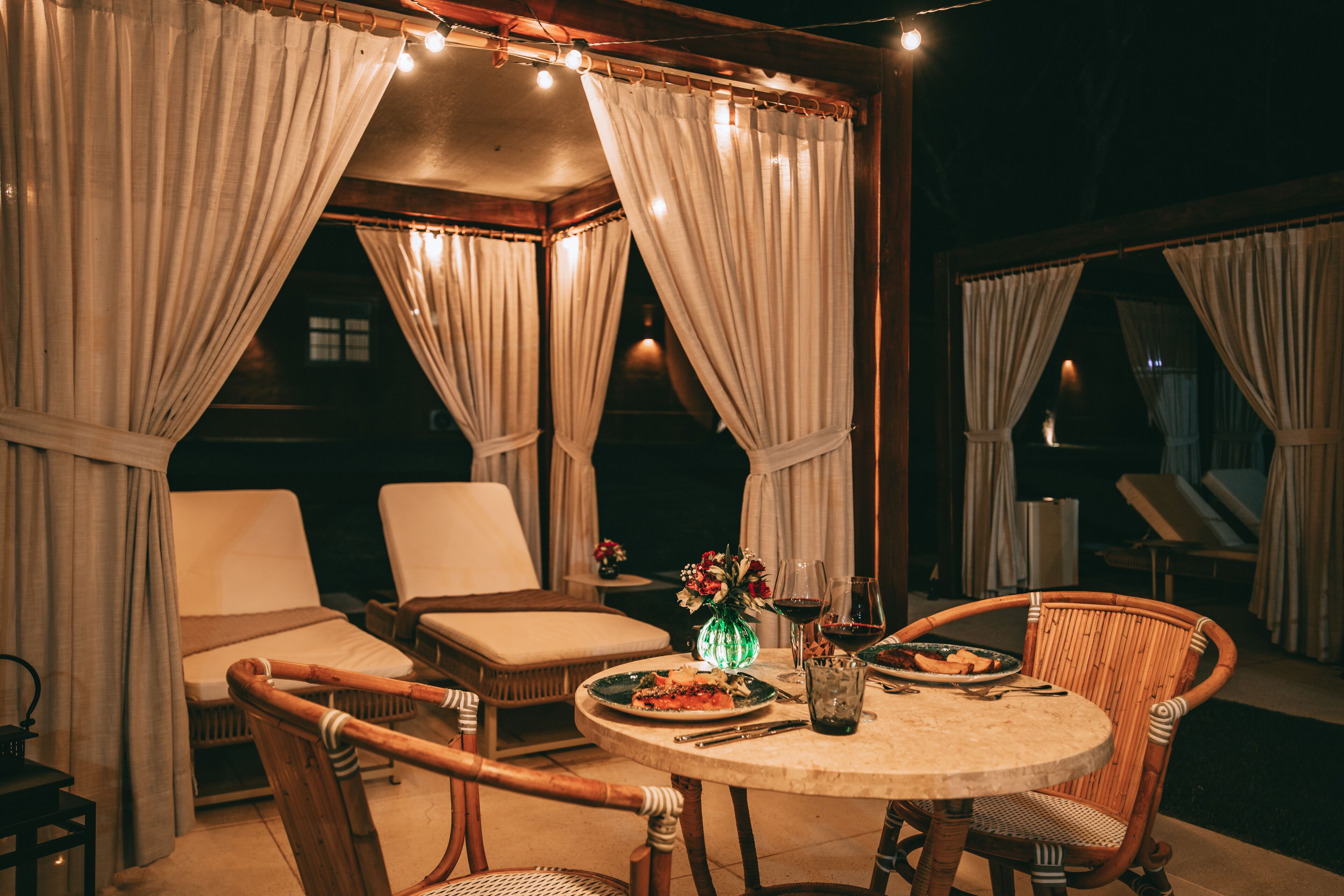 An outdoor seating area with a round table, wicker chairs, and a cushioned bench.