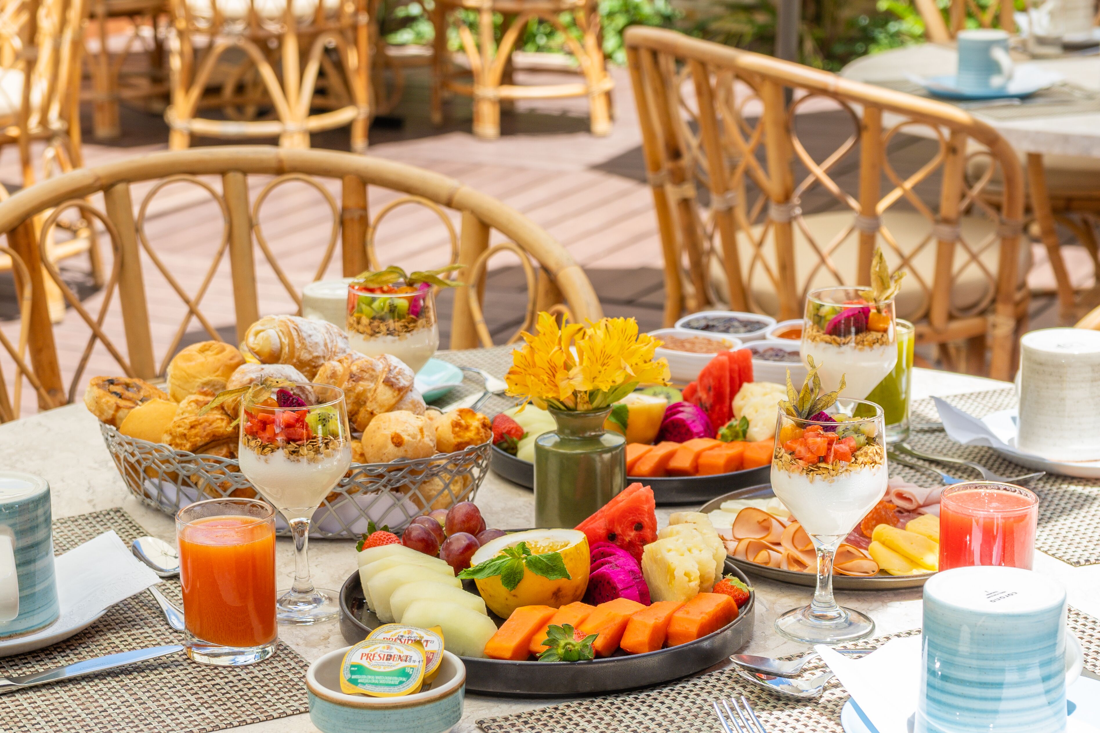 Buffet de l'esmorzar amb diverses fruites, pastissos i begudes sobre una taula.