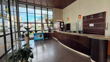 A reception area with a curved counter, a coffee machine, and a wall-mounted clock.