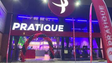 The exterior of a building with a large illuminated sign reading "PRATIQUE".