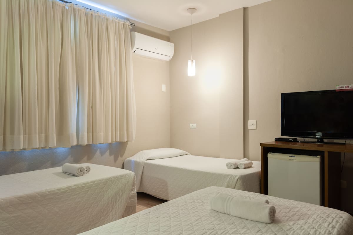 Een hotelkamer met twee bedden, een televisie, een minibar en een airconditioning.