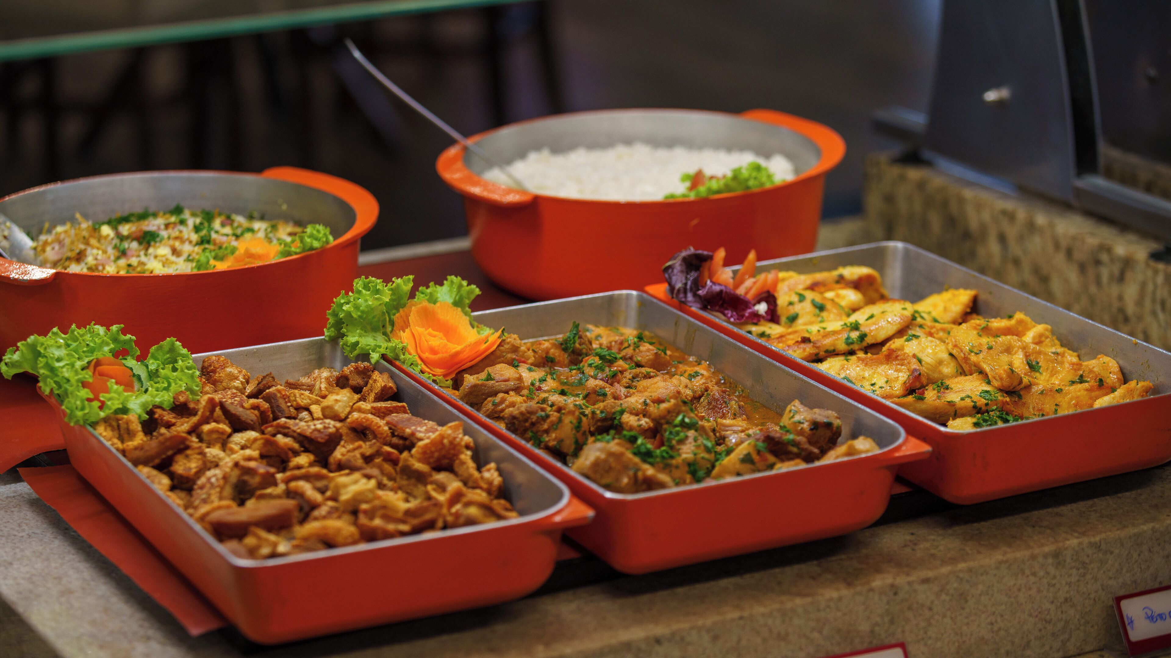 Un bufé con diversos platos, incluyendo arroz, carne y verduras.