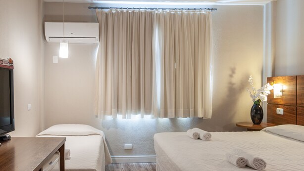 Et hotelværelse med to senge, et fjernsyn, aircondition og et lille bord.