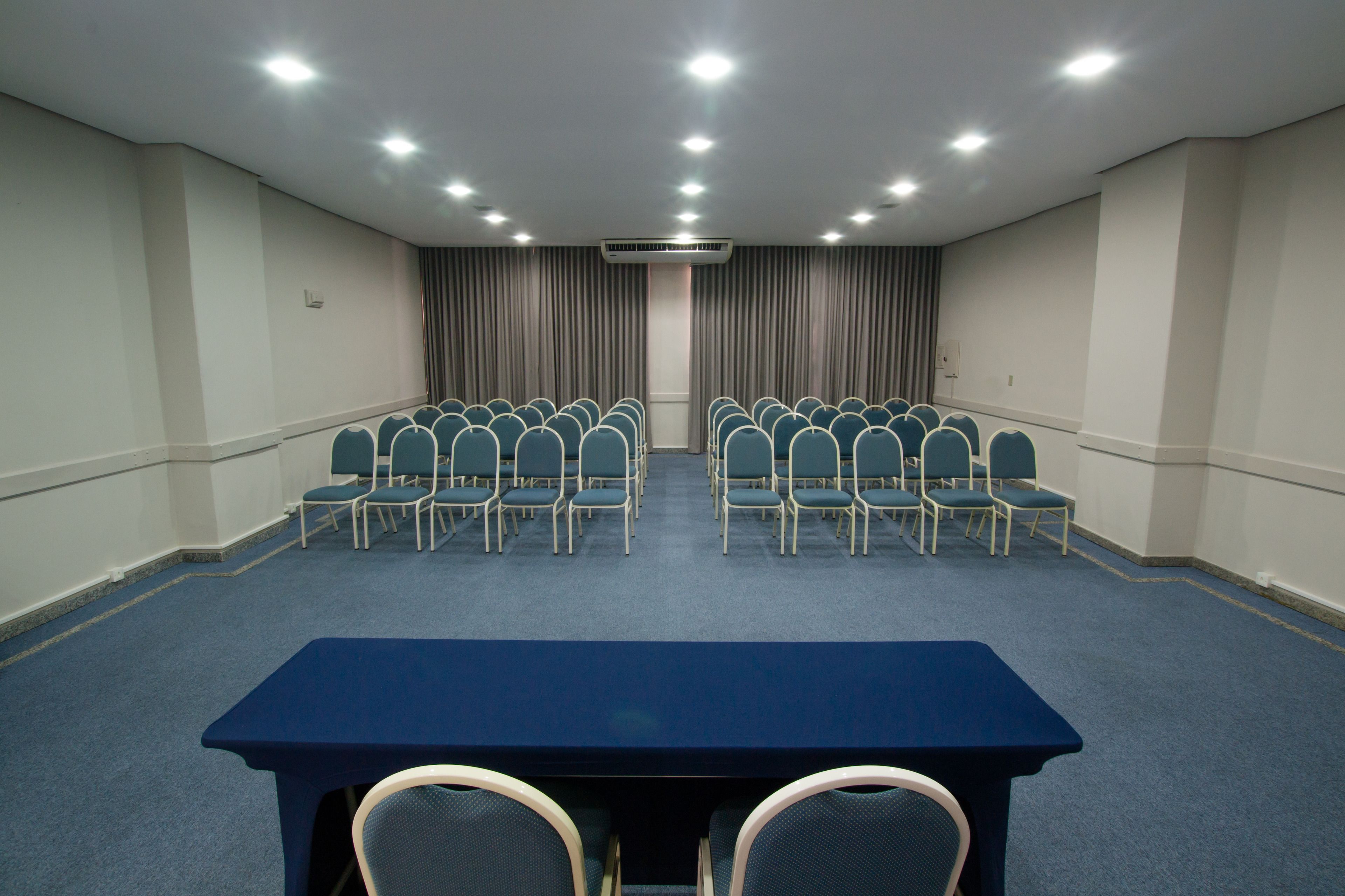 A conference room with rows of chairs, a long table, and a ceiling air conditioner.