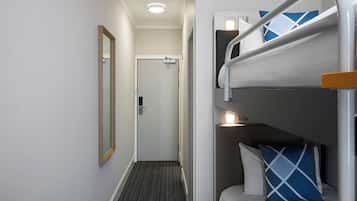 A bunk bed with a headboard, a mirror, and a door in the background.