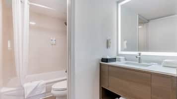 Un baño moderno con bañera, inodoro y tocador con espejo.