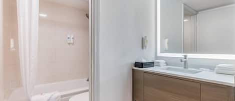 Un baño moderno con bañera, inodoro y tocador con espejo.