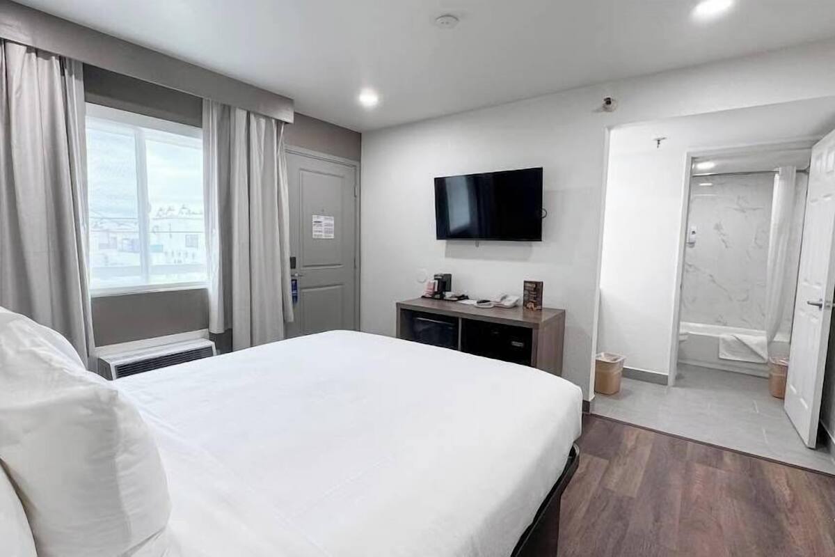 A hotel room with a bed, a TV, a desk, and a bathroom.