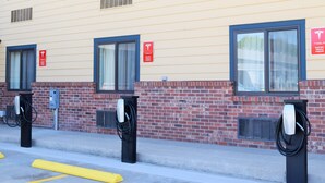 A row of Tesla electric vehicle charging stations along a building's exterior. - Baymont by Wyndham Pierre (Pierre)