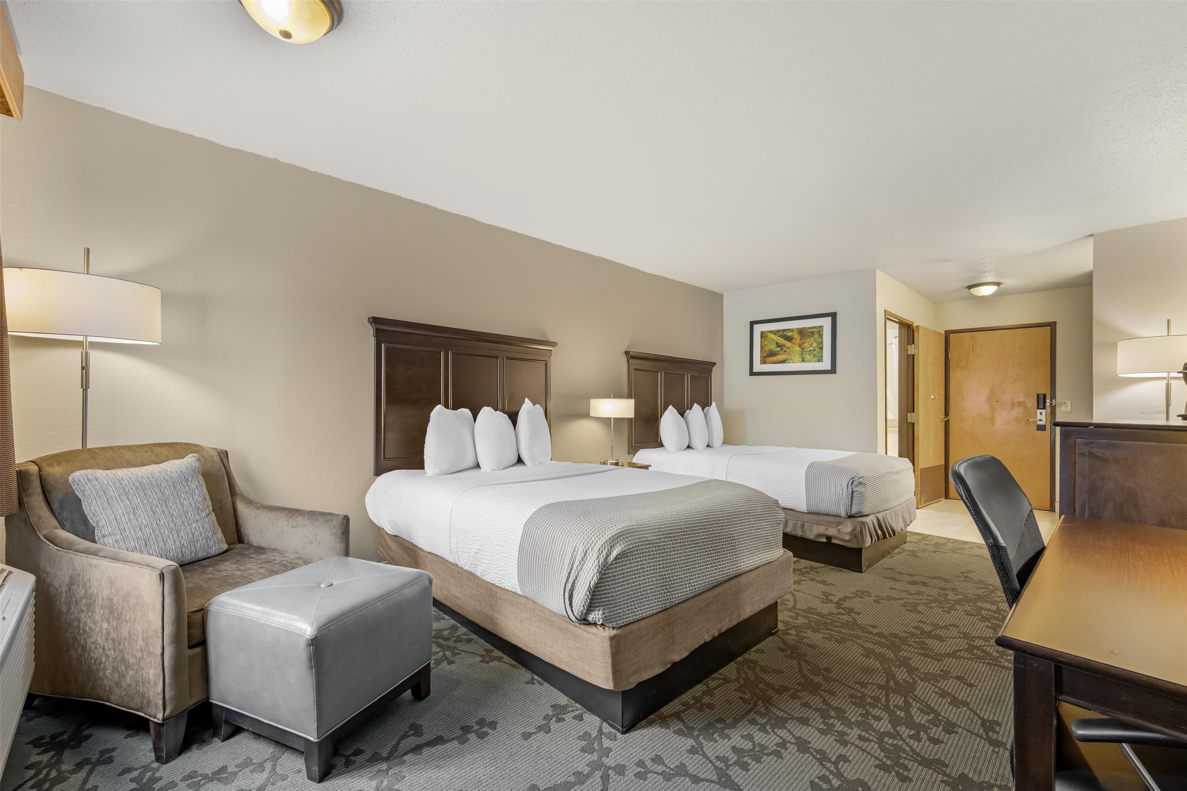 Een hotelkamer met twee bedden, een bank, een tafel en een stoel.