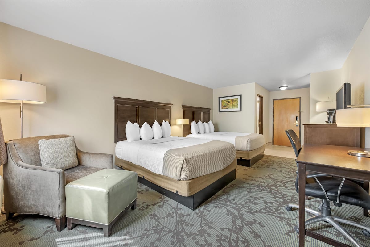 Ein Hotelzimmer mit einem großen Bett, zwei Nachttischen, einem Schreibtisch, einem Sessel und einer Couch.