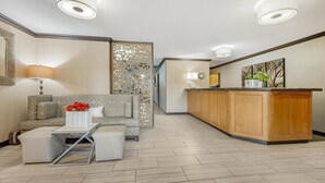 Een moderne hotel lobby met een bank, voetenbankje en een receptiebalie.