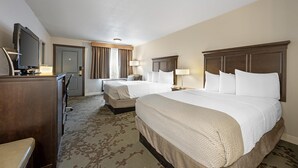 Een hotelkamer met twee bedden, een bureau, een flatscreen-tv, een dressoir en een kamerbreed tapijt met dessin.