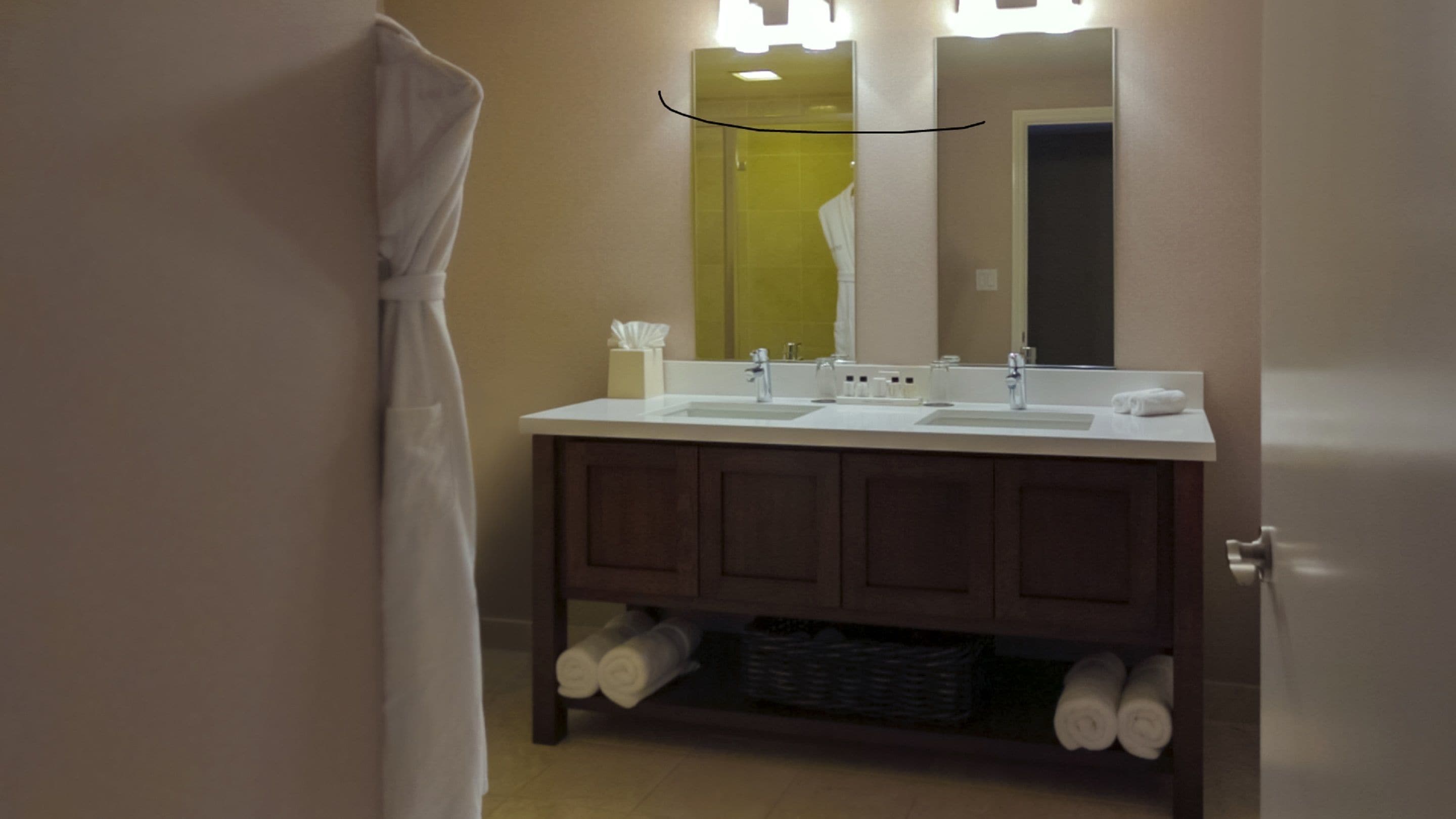 A bathroom with a double sink, a mirror, and a towel rack.