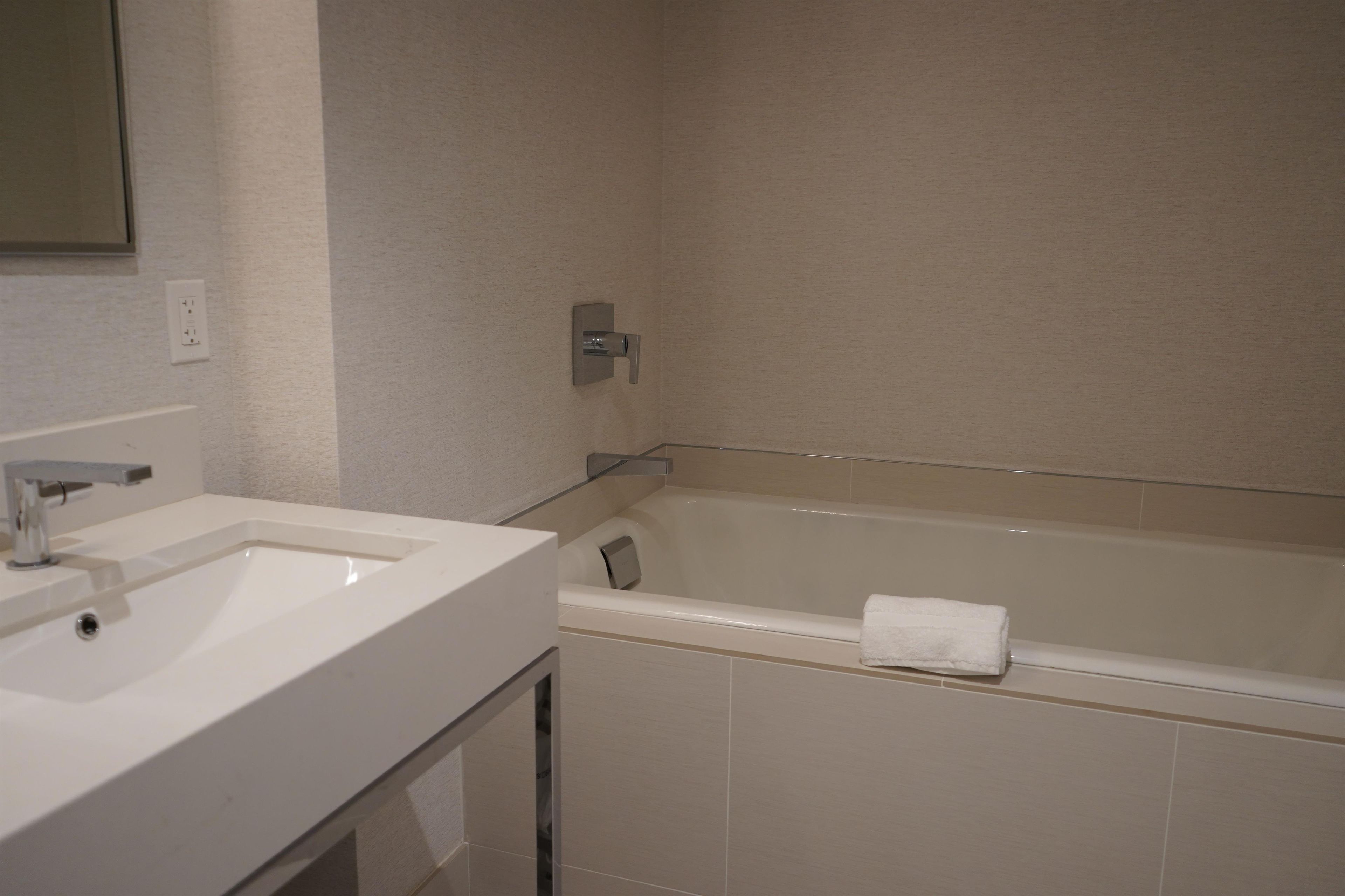 Un baño con un lavamanos blanco, un espejo y una bañera.