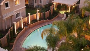 A residential building with a swimming pool surrounded by greenery and a covered patio area. - The Grand Hotel (Sunnyvale)