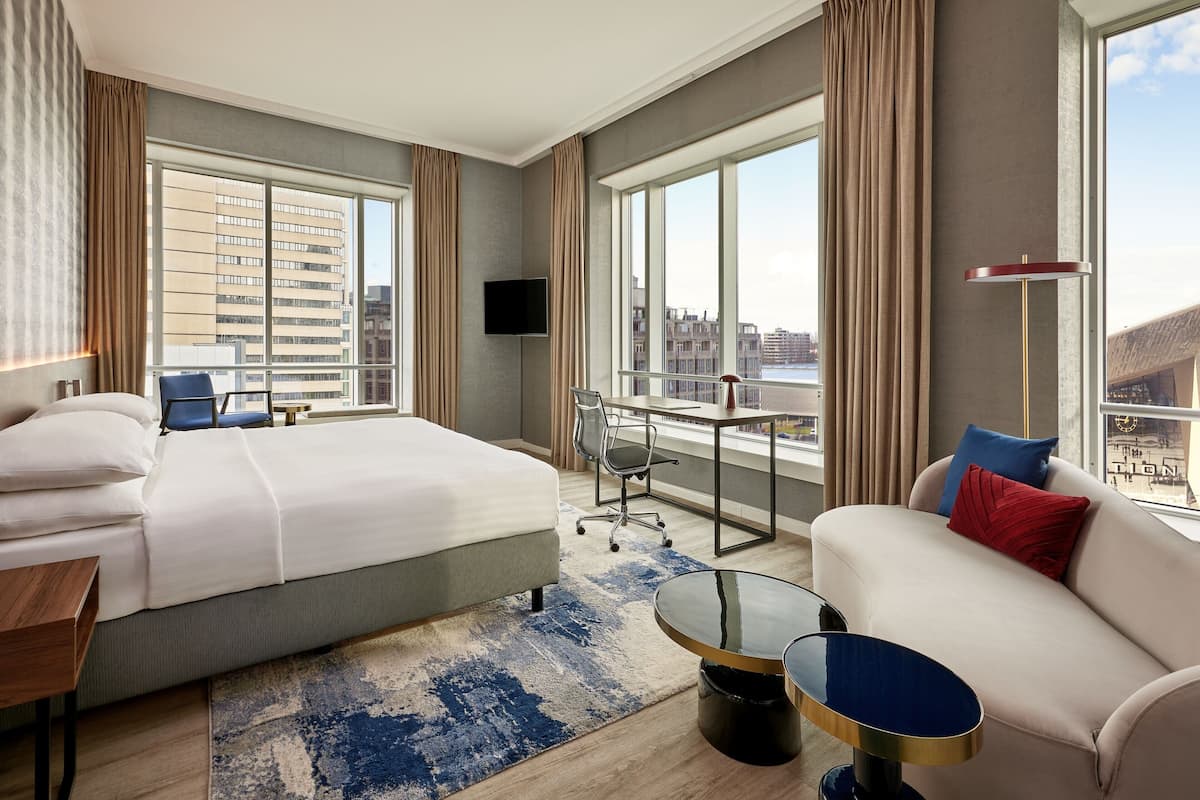 Una habitación de hotel con una cama grande, un sofá, un escritorio y un televisor.