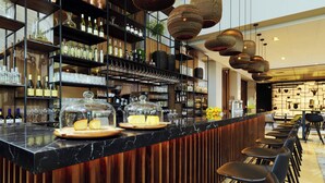 Una zona de bar con encimera de mármol, botellas de vino, copas y un diseño de paneles de madera.