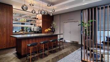 Una cocina moderna con una isla central, taburetes de bar, iluminación colgante y vistas al área de estar a través de una puerta corredera.