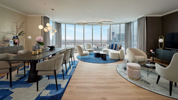 Una sala de estar moderna con comedor, ventanas amplias y vista a la ciudad.