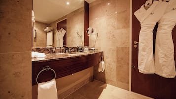 A modern bathroom with a marble countertop, a large mirror, and a wooden door.