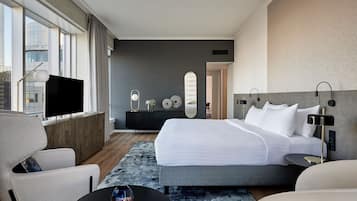 Una habitación de hotel moderna con una cama grande, un televisor, un sofá y un escritorio.