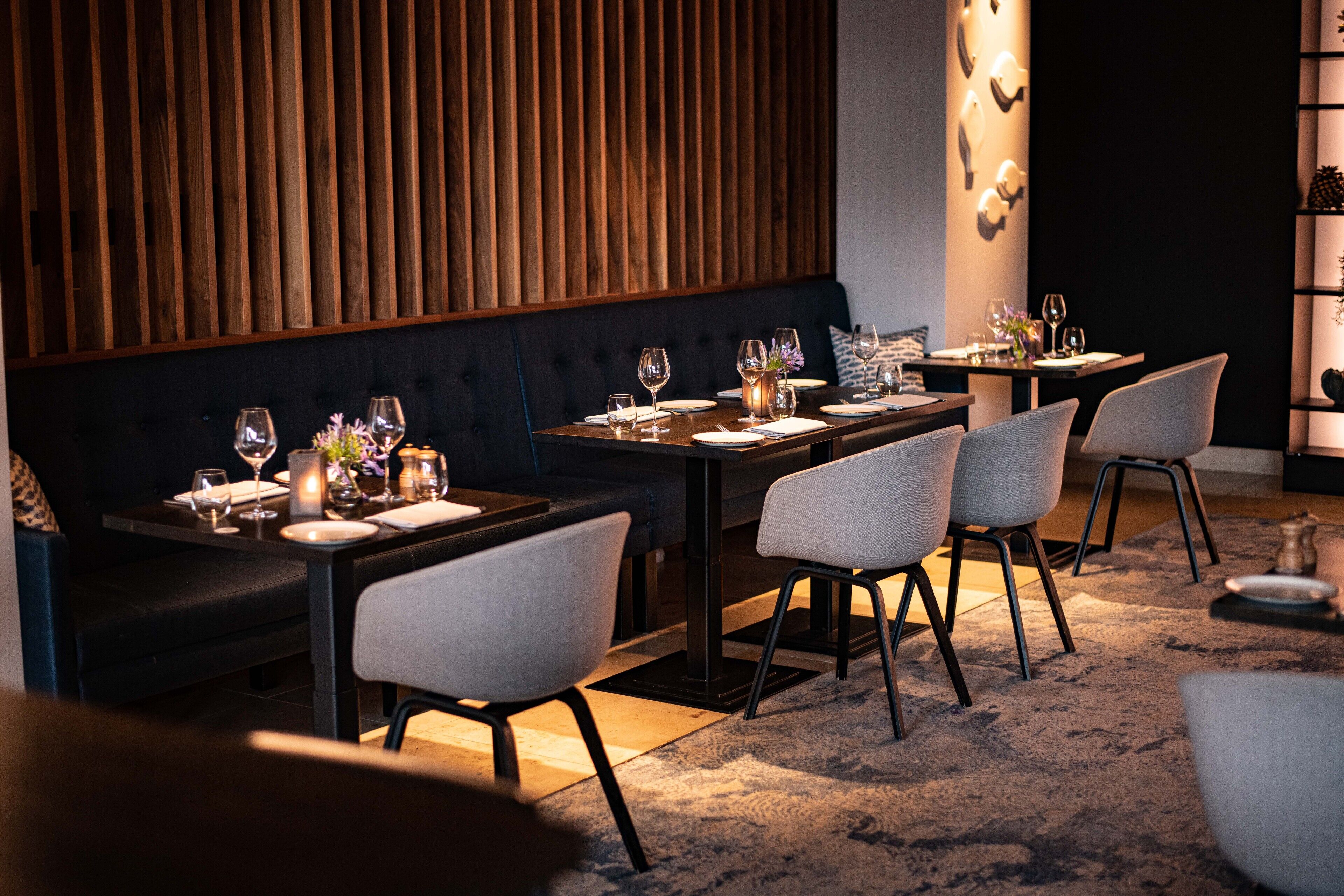 A restaurant with dark wood paneling, modern furniture, and a cozy ambiance.
