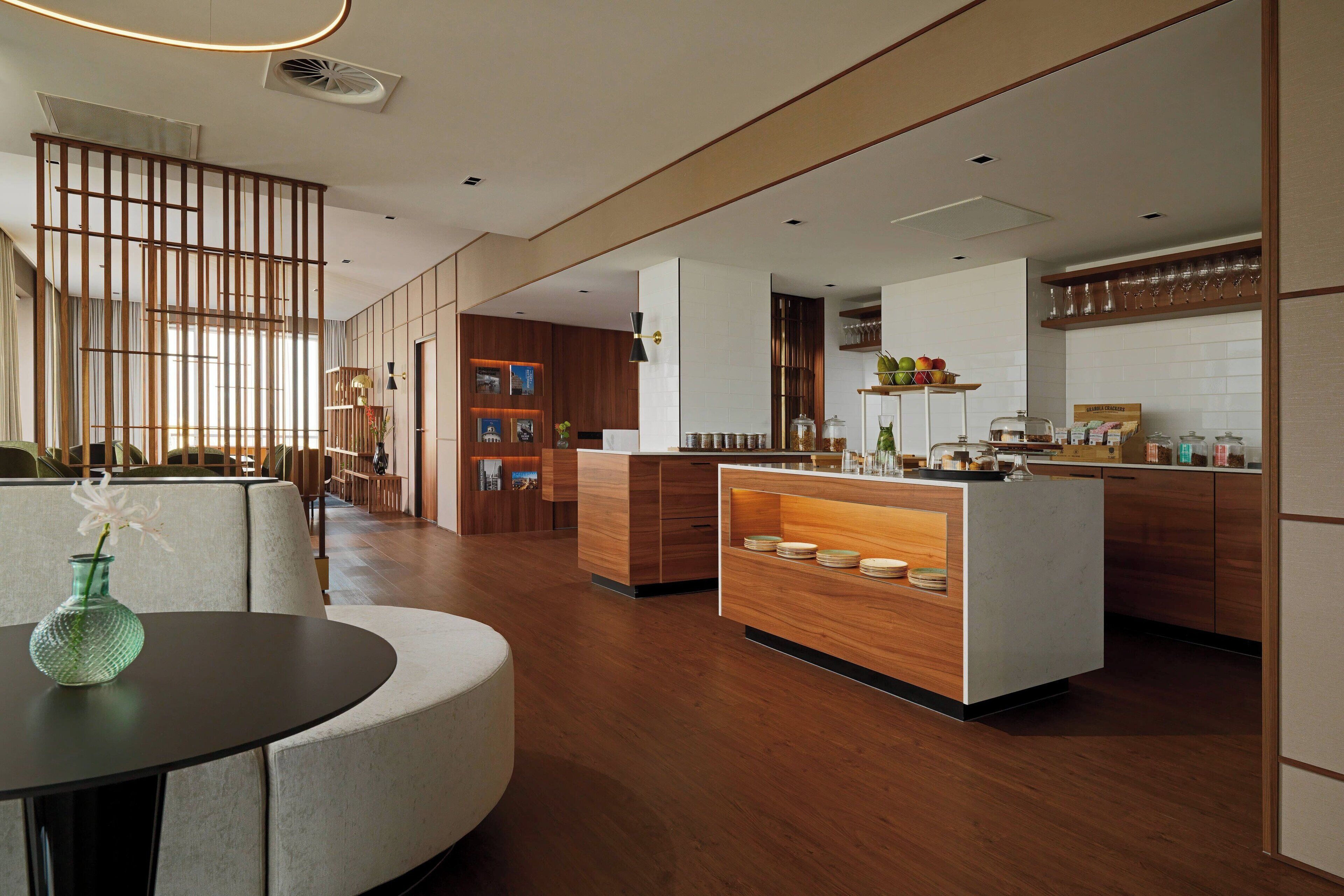A modern kitchen with wooden cabinets, a central island, and a dining area with a round table and a vase.
