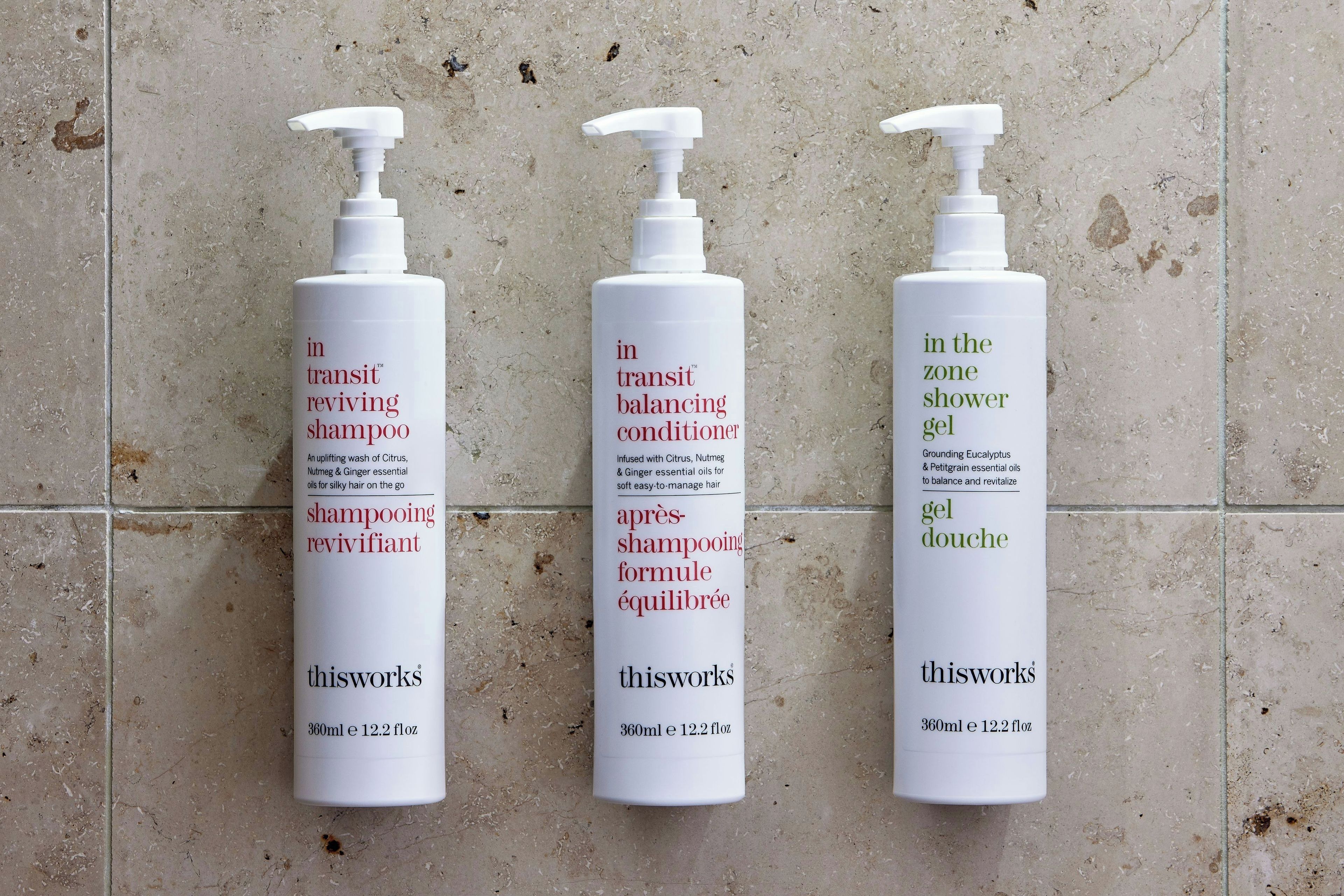 Trois flacons de produits de soins personnels de la marque thisworks sont posés sur un sol carrelé.