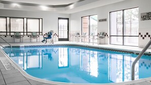 Ein Hallenbad mit klarem Wasser, umgeben von gefliesten Wänden und Fenstern.