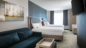Ein Hotelzimmer mit Bett, einer Couch, einem Fernseher und einem Bild an der Wand.