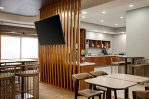 A modern restaurant interior with wooden partitions, a bar area, and seating arrangements. - Springhill Suites by Marriott Tulsa (Tulsa)