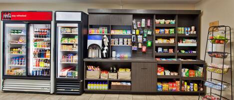 A self-service beverage station with Coca-Cola and other drinks, a coffee machine, and a variety of snacks and groceries.