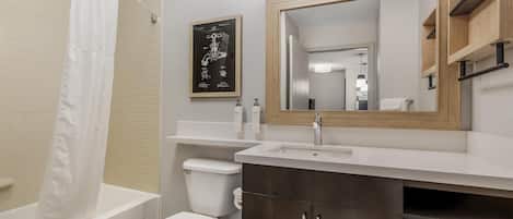 Un baño moderno con bañera, inodoro y tocador con espejo.