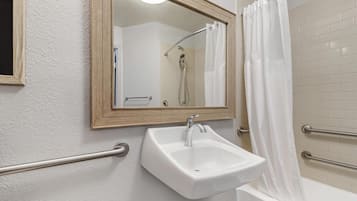 A bathroom with a white sink, a mirror, and a shower.