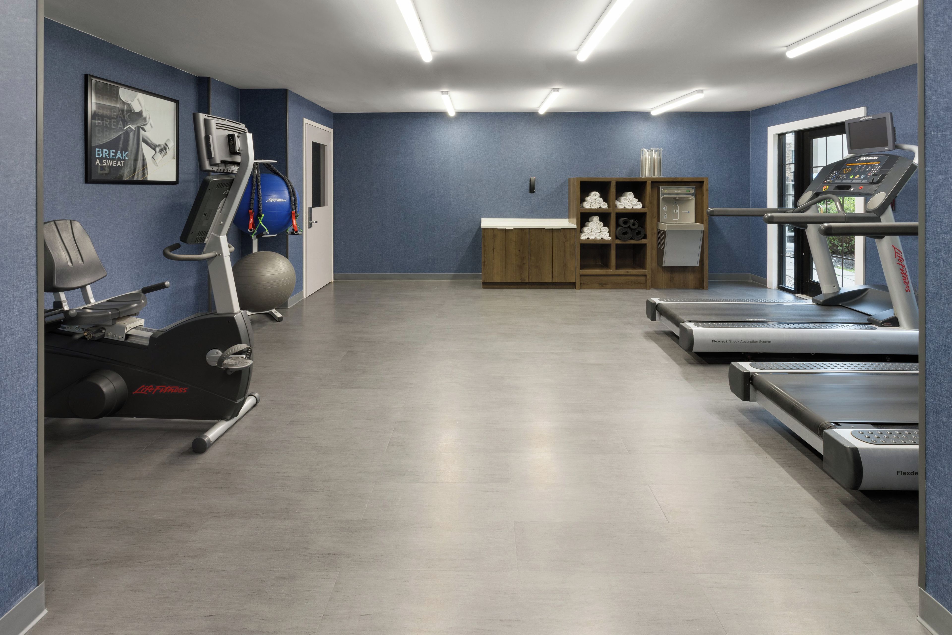 Un gimnasio con cintas de correr, una bicicleta estática y una máquina de remo.