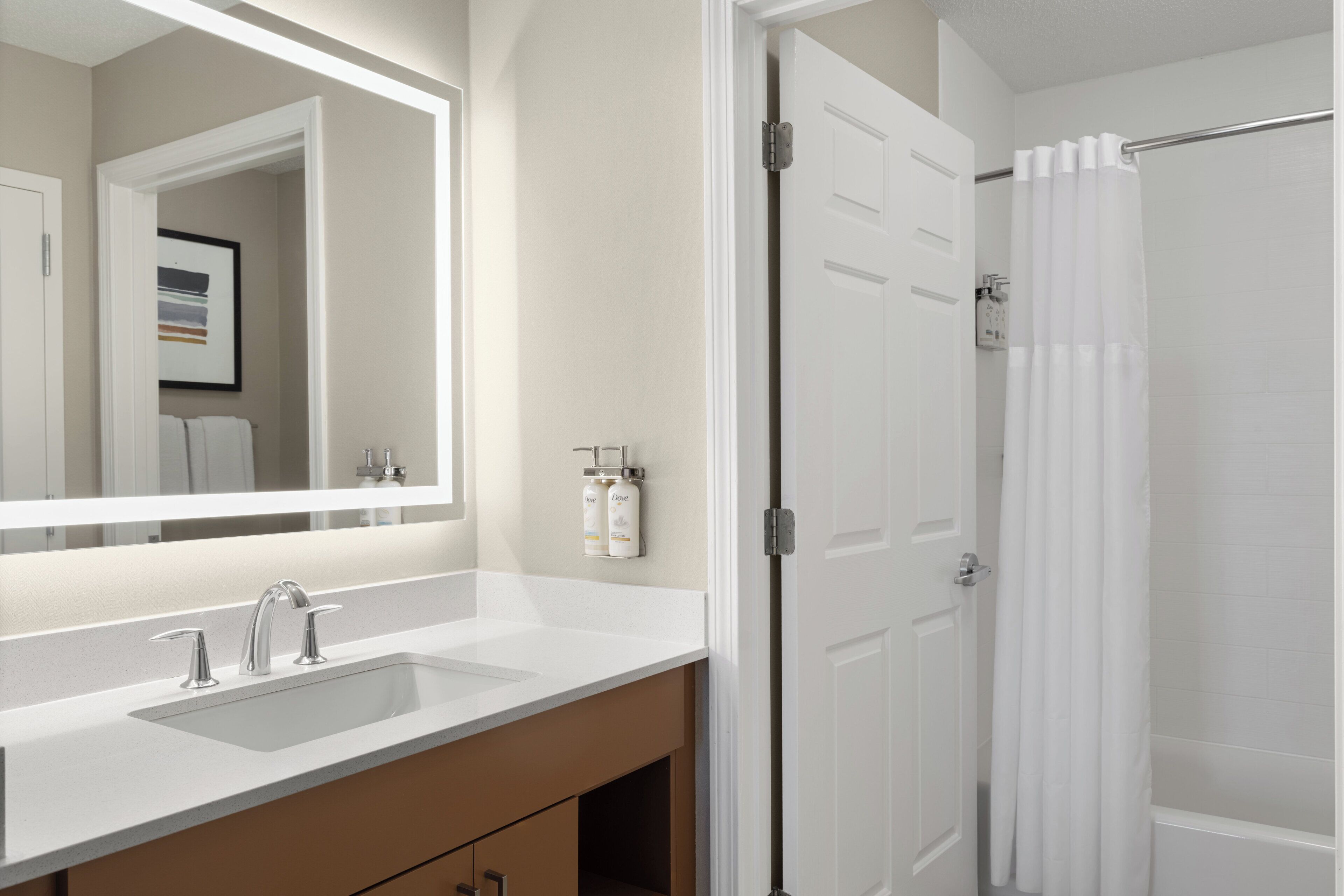 A bathroom with a white sink, two faucets, a mirror, and a shower curtain.