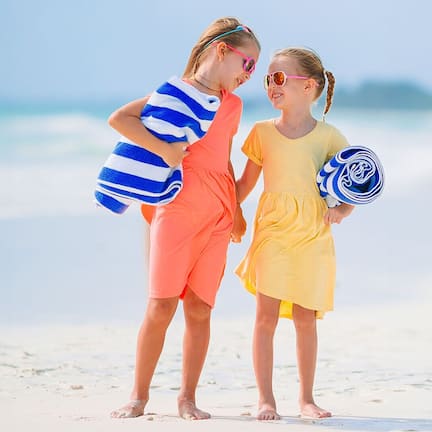 Two people on a beach with a clear sky and ocean in the background.