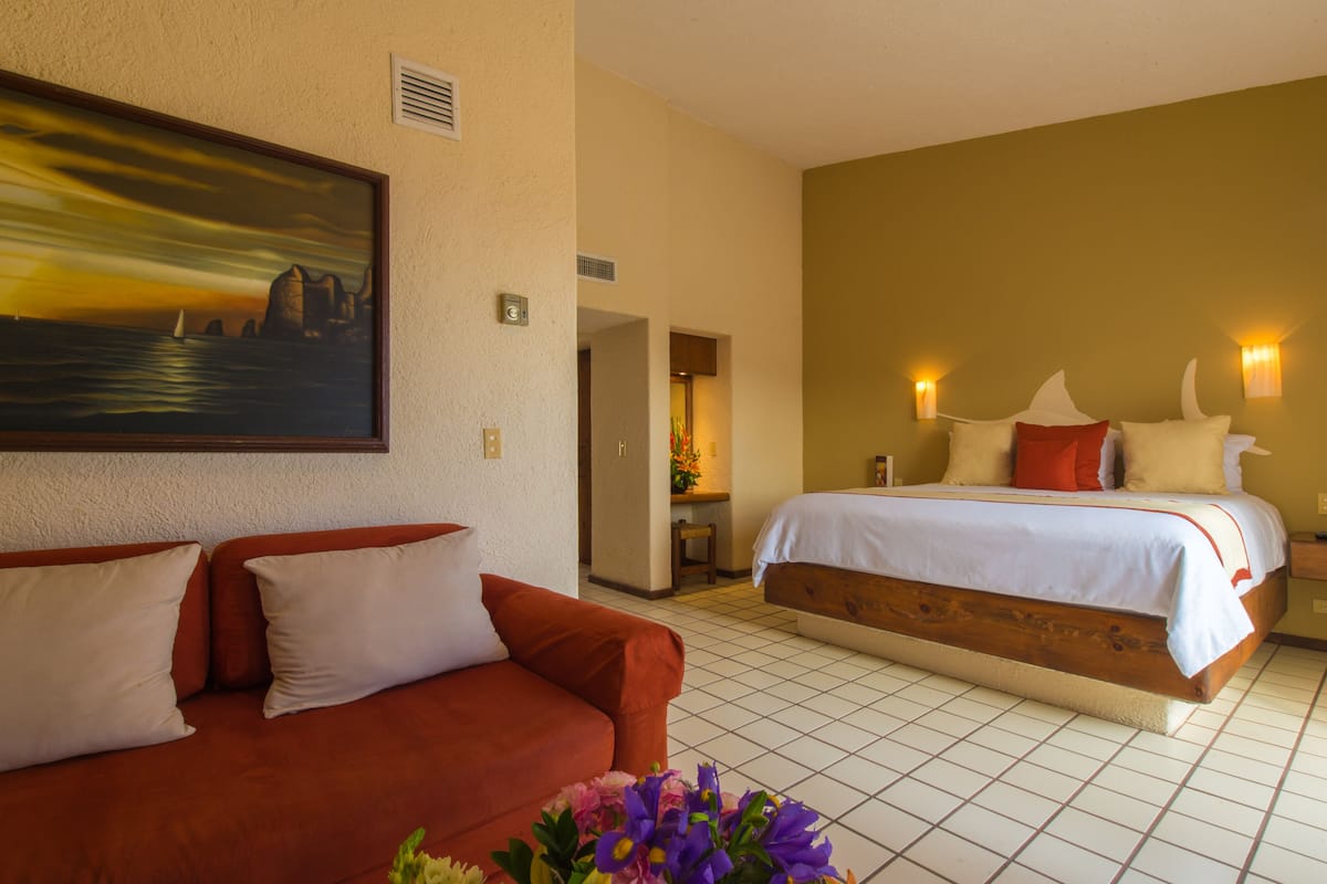 A hotel room with a bed, a sofa, and a painting on the wall.