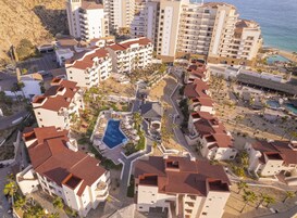 A resort with multiple buildings, a central swimming pool, and a beach area.