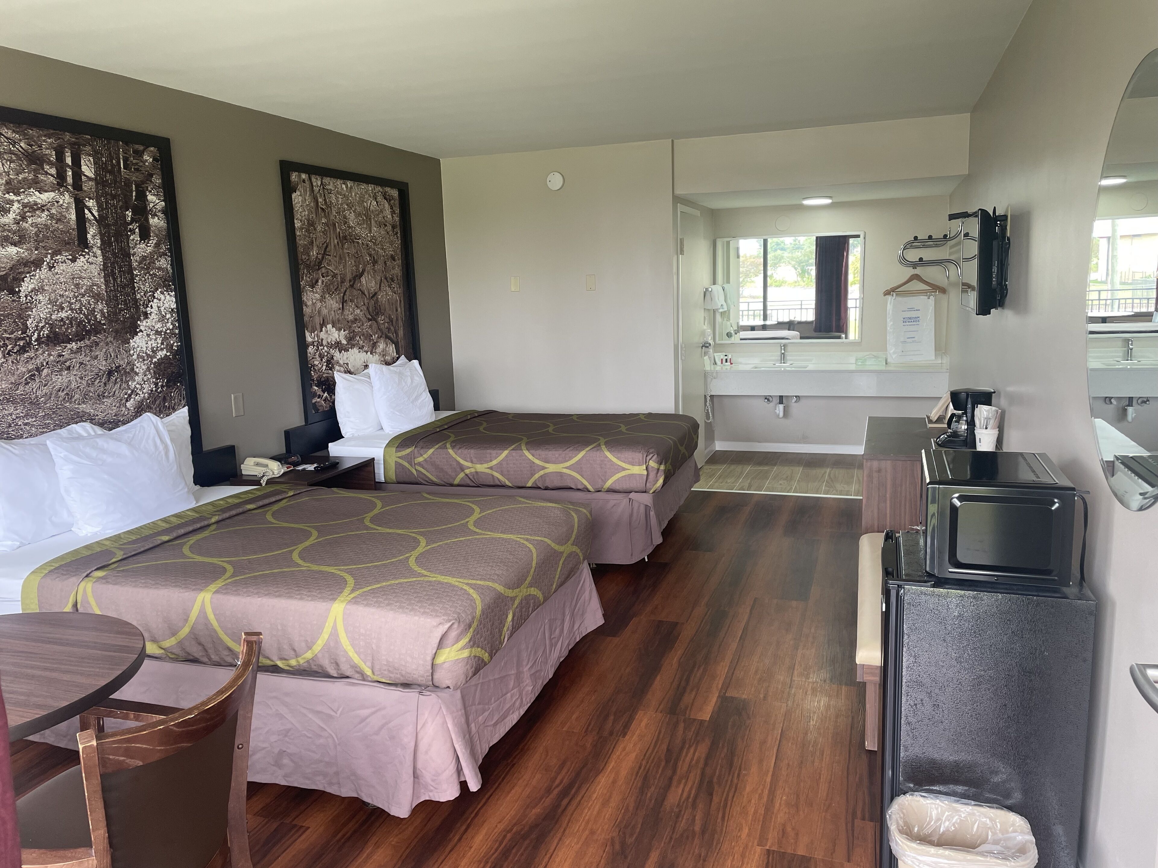 Habitación de hotel con dos camas, un escritorio, una silla, un microondas y un lavabo.