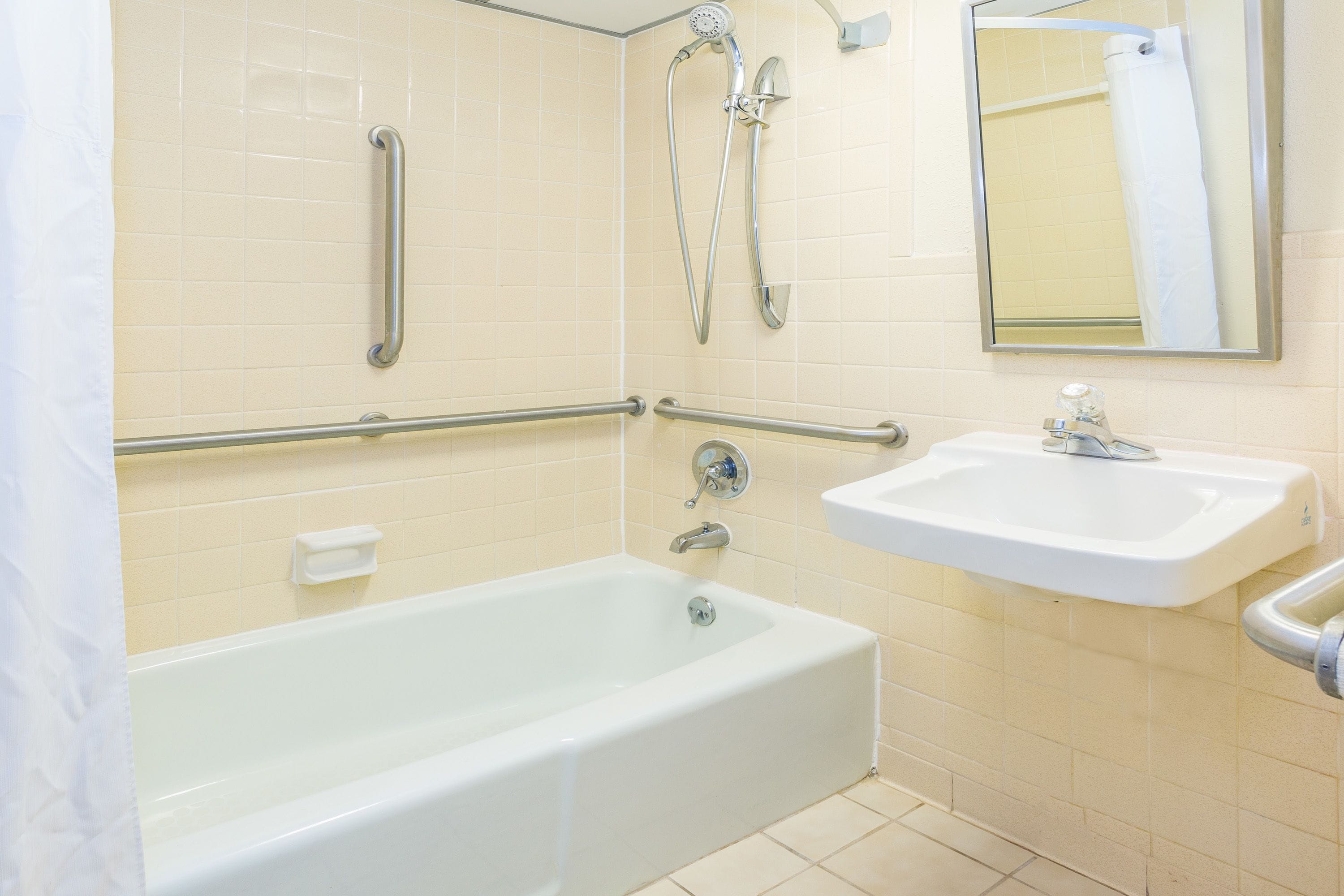 A bathroom with a bathtub, a sink, a shower, and grab bars.