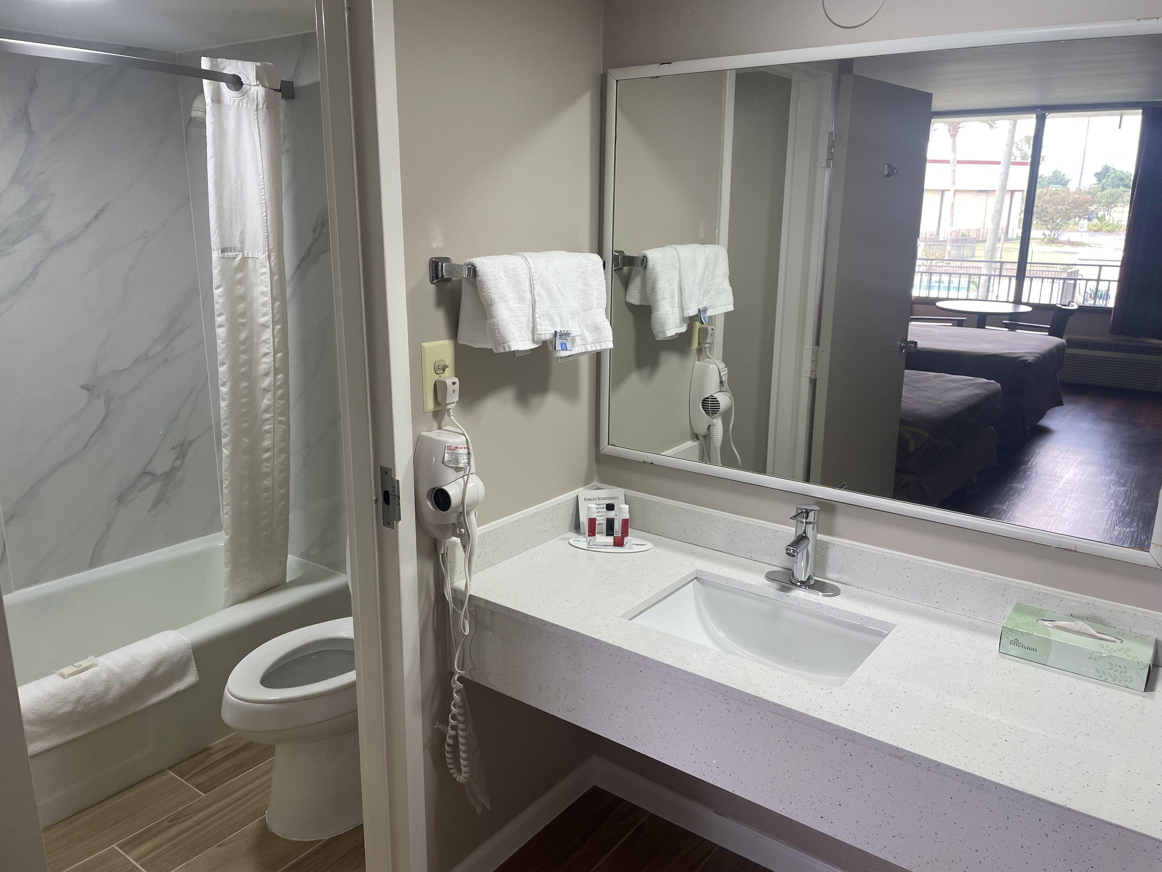 A bathroom with a white sink, a mirror, a shower curtain, and a toilet.