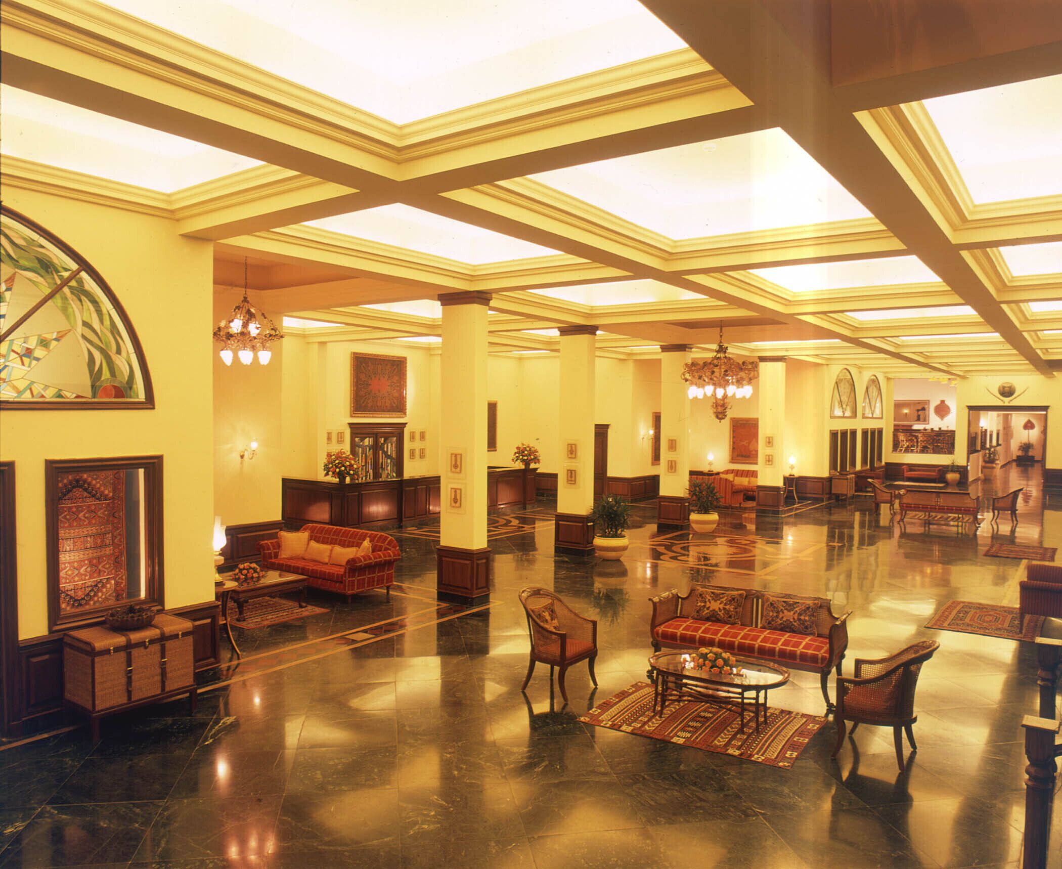 A spacious lobby with high ceilings, chandeliers, and a polished marble floor.