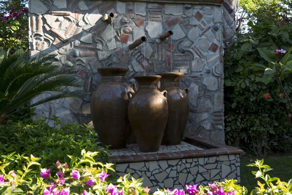 A stone wall with three large vases and a water feature.