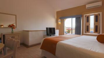 A hotel room with a bed, a television, a desk with a chair, and a window with a view.