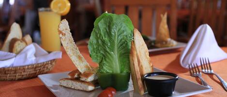 A plate with a salad, bread, and a small bowl of sauce.
